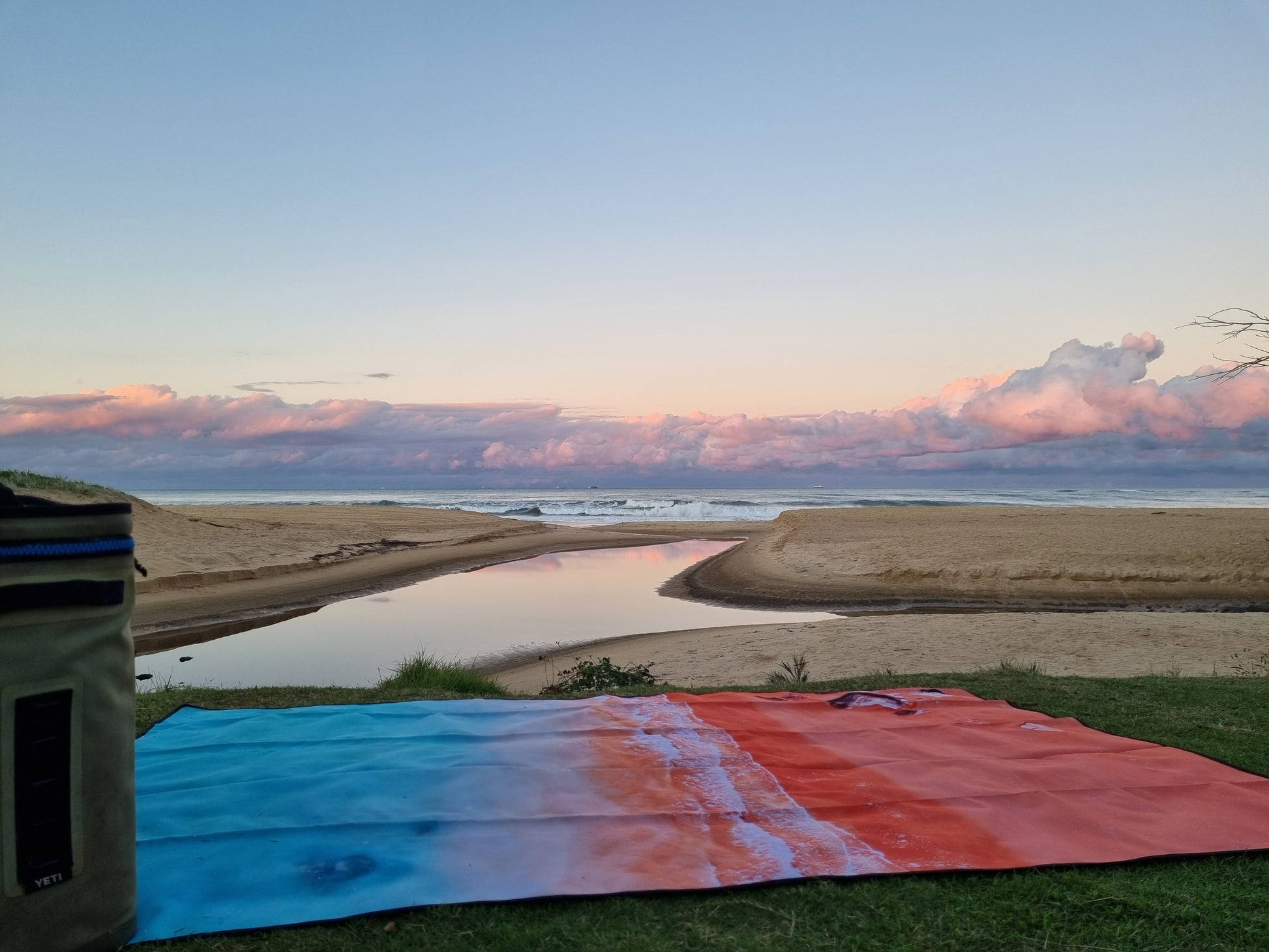 Kimberley Beach MatExclusive design by Trip In A VanThe Kimberley; Inspired by the turquoise blues and red pindan sands of Roebuck Bay, Broome WA FINALLY a mat you can throw down anywhere, anytime! The top side of our beach mats are made from an exceptionally durable, hard-wearing, yet soft feeling Oxford fabric. The rugged versatility of this material is perfect for outdoor conditions due to its water and mildew resistant qualities. Watch the spilt drinks bead off, and wipe clean for an instant dry feeling