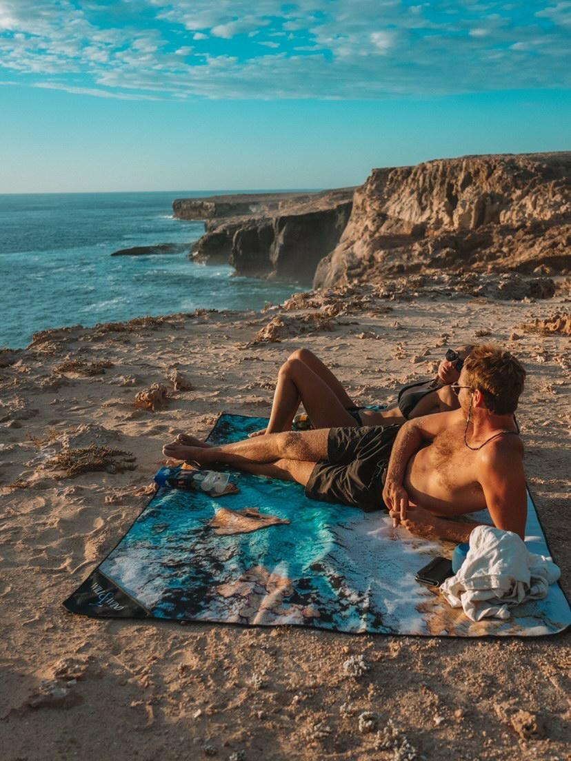 Kalbarri Beach MatDesign Inspired by Blue Holes in Kalbarri, WA "In the cold morning light, we float in the crystal clear rock pools of Kalbarri.We fly the drone and witness the contrast of colours and textures;blue water ripples, pastel pink windswept sand, earthy rock layers" FINALLY a mat you can throw down anywhere, anytime! The top side of our beach mats are made from an exceptionally durable, hard-wearing, yet soft feeling Oxford fabric. The rugged versatility of this material is perfect for outdoor c
