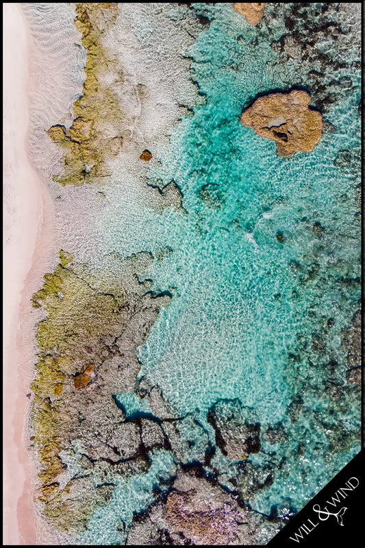 Aerial view of a coastal landscape with turquoise water and rocky shore.